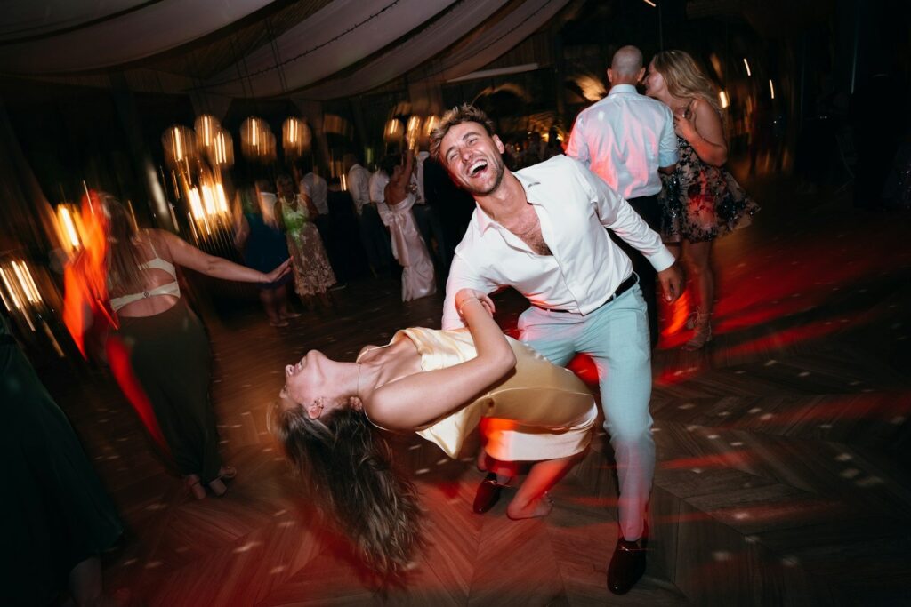 Lachende gasten dansen uitbundig op een bruiloftsfeest, vastgelegd met flits en bewegende lichtstrepen