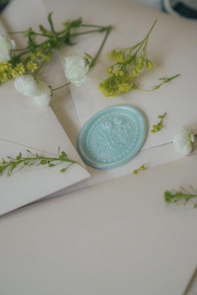 Witte enveloppen met een mintgroene lakzegel en kleine witte bloemen