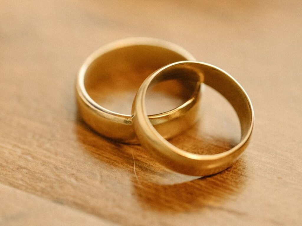 Twee gouden trouwringen op een houten ondergrond