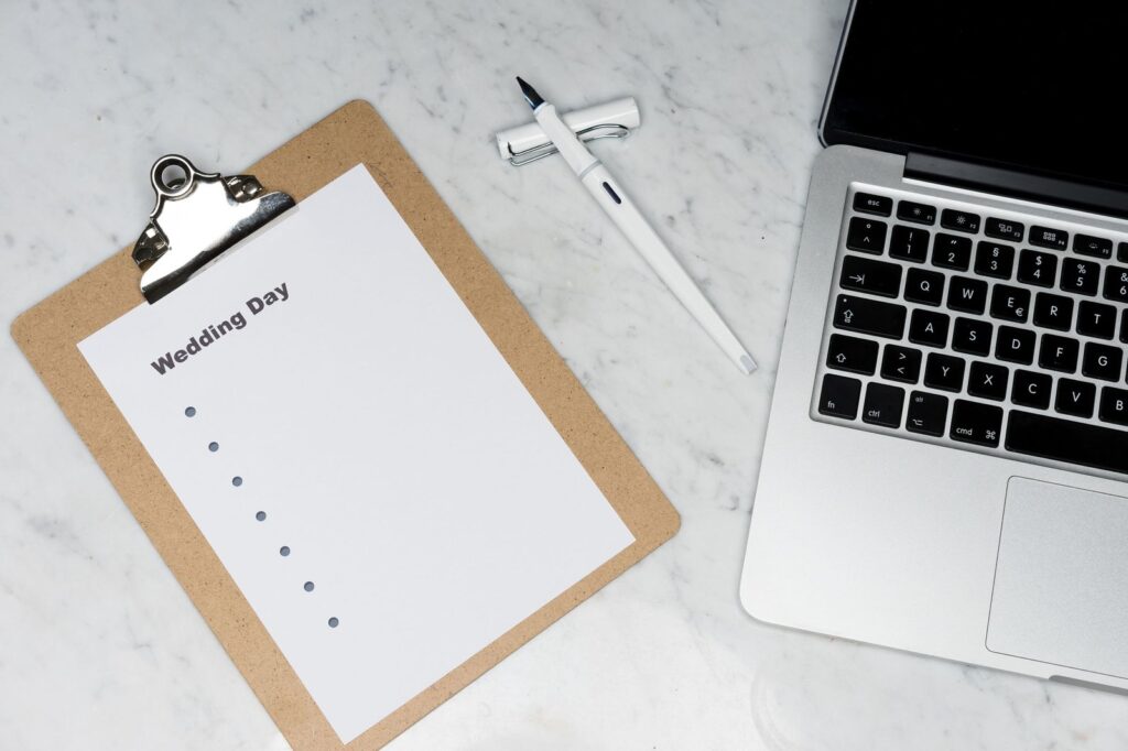 Flat lay van laptop, klembord en pen als planning voor een bruiloft budget