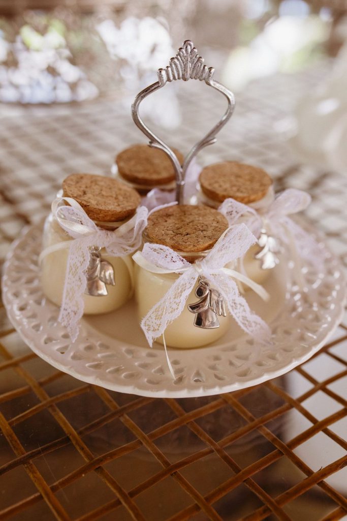 Potjes met kurken deksel, kanten lint en belletjes op een etagère als trouwbedankje