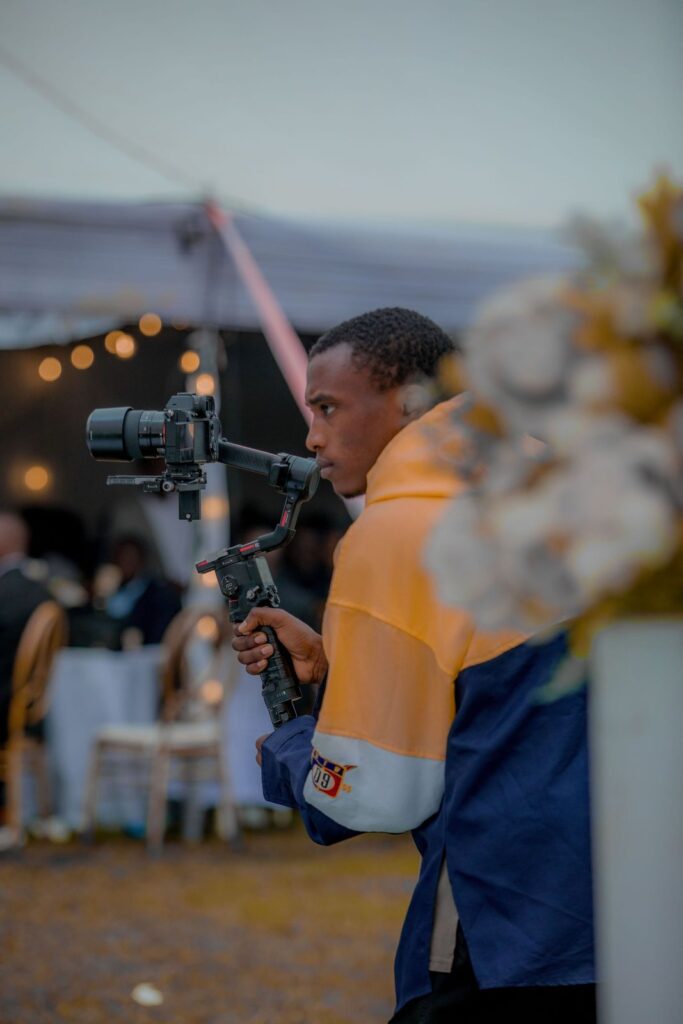 Videograaf filmt met een camera op een gimbal bij een feesttent met lichtjes en bloemen