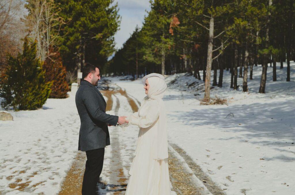 Bruidspaar hand in hand op een besneeuwd bospad tijdens een winterbruiloft